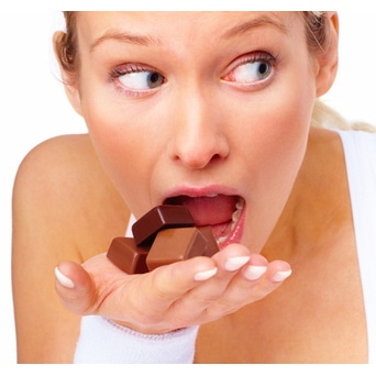 Young cute woman trying to eat chocolates over white background