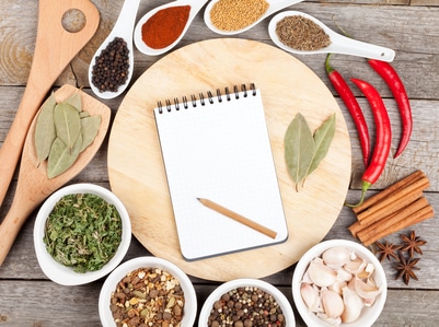 Herbs and spices on wood table background with blank notepad for copyspace