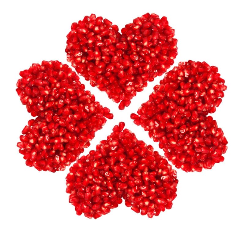 pomegranate seeds in heart shape isolated on white background